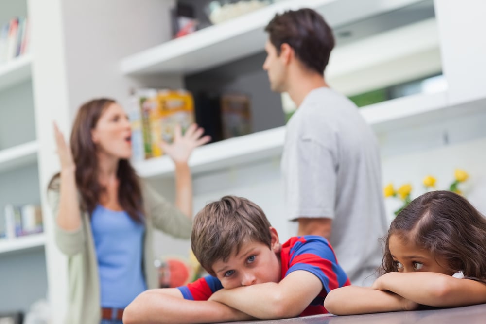 Couple arguing behind their children in the kitchen